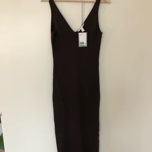 OANVÄND! HM brun stickad klänning S - Lappen kvar pga helt oanvänd! Går att ha med en slit eller knäppt med knappar på sidan av klänningen, superfin! 