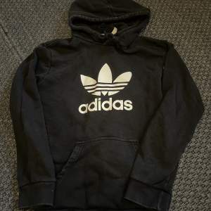 Adidas hoodie i storlek S. Köpt från stadium. Den är svart men lite gråa defekter som kommit när man tvättat den.