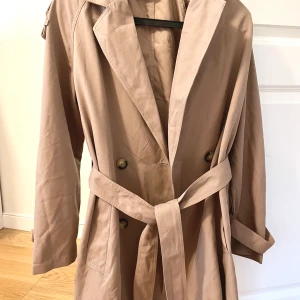 Kort trenchcoat från Vero Moda, storlek XS - Kort trenchcoat från Vero Moda, storlek XS. Väldigt fint skick. Modellen är egentligen längre men jag har sytt upp hos den hos en skräddare. Frakt tillkommer 🤍