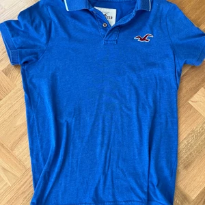 Hollister Piké  - En fin Hollister piké i väldigt len bomull med härlig blå färg. Herr storlek M.  Använd sparsamt, gott skick och felfri! Nypris: 750kr.  Pris: 200kr