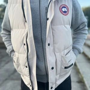 Canada goose väst stl L-M beige/vit - Helt ny canada goose väst i storlek L men passar M utan problem, endast använd utomhus 1 gång men kan inte behålla den utav olika skäl. Den är äkta och kan skicka bild på lazertagen om så vill. Är även intresserad i byten. Skriv för fler bilder eller info