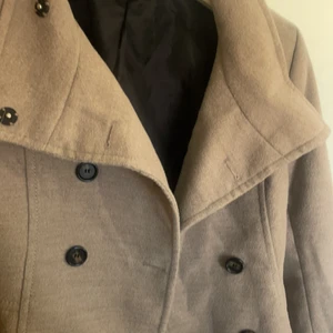 Beige, kort kappa - En beige kappa ifrån Hm, en kortare modell men täcker ändå rumpan 