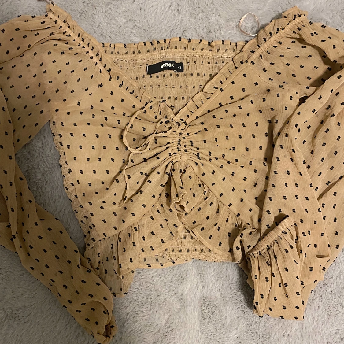 Beige tunn långärmad tröja, Knut framme vid tröjan. 