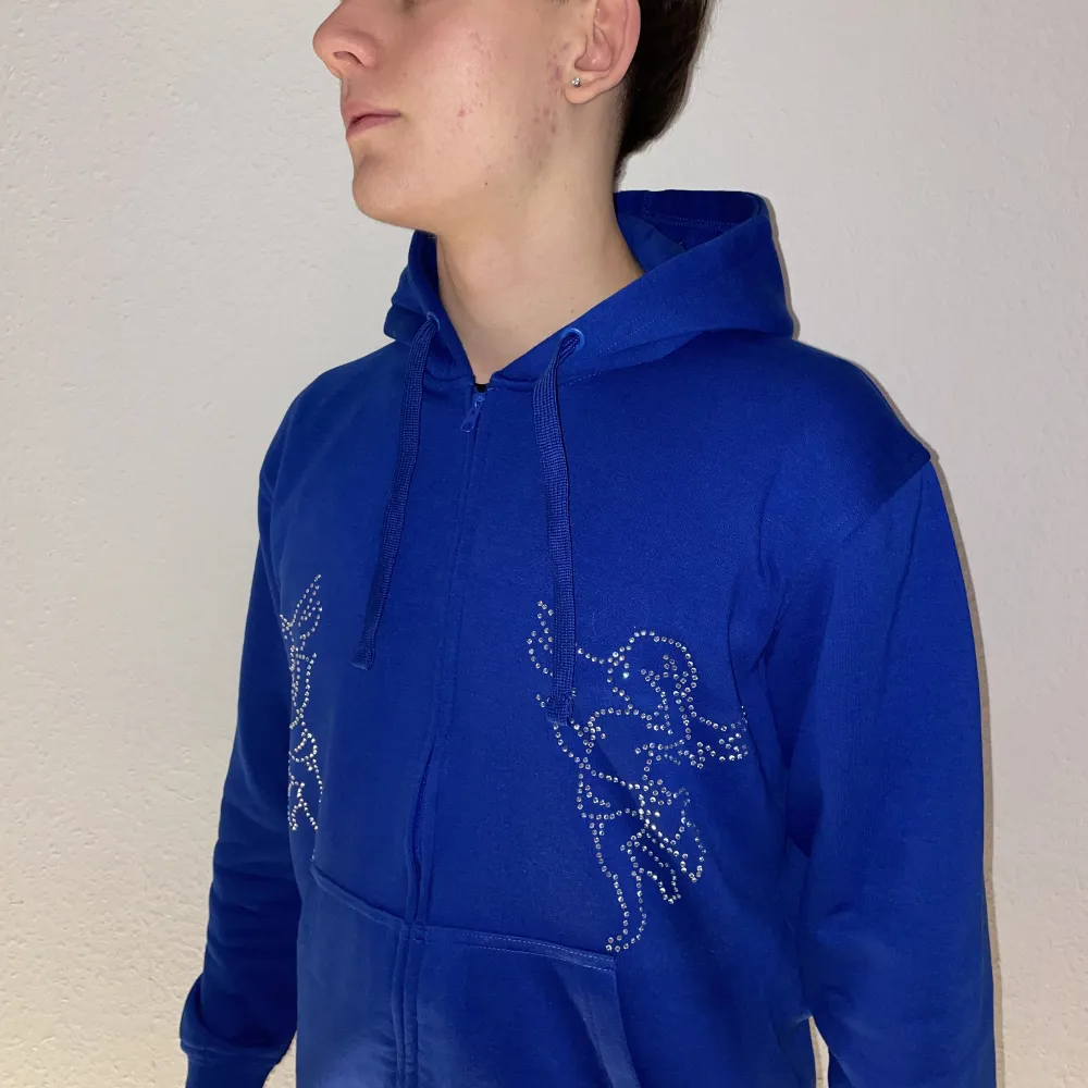 Blå hoodie designat med Rhinestine, finns även i en svart modell!. Hoodies.