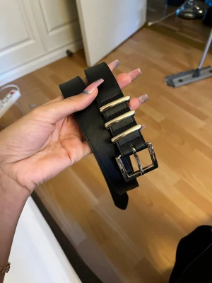 Bälte  - Svart bälte med guldiga spänne och detaljer. Se andra och tredje bilden för att se bruksslitage