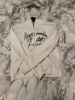 Kort vit zip up hoodie - En kortare bit hoodie som slutar lite under naveln. Den har dragkedja 