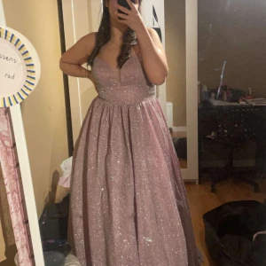 Klänning glittrig - Balklänning glittrig i storlek 40. Använd endast 1 gång.  Finns ett hål som går att laga vid midjan.
