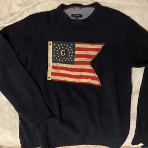 Stickad tröja Gant - En stickad ulltröja från gant i mycket bra skick! Den har den amerikanska flaggan sydd på framsidan och påminner om Den populära ralph lauren tröjan. Om annonsen finns kvar finns varan kvar. Den har inga defekter 