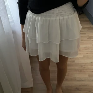 Vit volangkjol från Chelsea - Superfin och trendig volangkjol från Chelsea! Perfekt nu inför sommaren. Kjolen är använd bara  1 gång och är i helt ny skick utan några defekter. Den är väldigt stretchig vilket gör att den passar fint för flera storlekar (xxs-m). Kjolen kommer tyvärr inte till användning längre! Köpt för 450kr. Skriv i chatten för fler bilder. Buda bara ifall du ska köpa! KÖPAREN STÅR FÖR FRAKTEN.