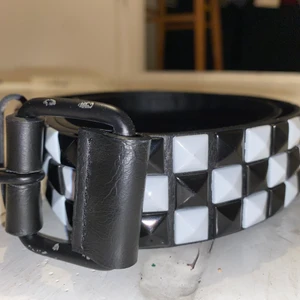 Nitskärp - Coolt nitskärp i schackrutigt mönster. I rätt fint skick förutom att det har lossnat svart färg kring metallen (se bild). I PU material.  Katt i hemmet. Kan mötas upp i Uddevalla om ej så står köparen för frakten. 