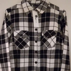 NY & OANVÄND Svart-vit rutig flanellskjorta för dam/tjej. Strlk: 34/XS-S. - Helt NY och oanvänd snygg svart/vit rutig mjuk/len flanellskjorta för dam/tjej, från Gina Tricot. Storlek: 34/XS-SMALL. Material: Bomull. Helt felfri. Etiketter/tags sitter kvar sedan inköpet.