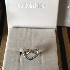 Superfin metallic charmig rostfritt stål knuten hjärtring från Calvin Klein.