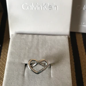 Calvin Klein ring  - Superfin metallic charmig rostfritt stål knuten hjärtring från Calvin Klein.