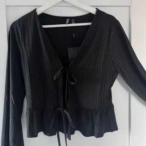 Topp - Svart topp med knytning framtill. Storlek L men passar absolut som en M.