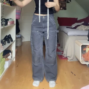 Carhartt carpenter double-knee work pants - Carhartt double-knees, slitna men det är det som är najs. Det finns många fickor. Midjemått:  38cm Innerbenslängd: 78cm, observera att det finns slitningar på byxorna 