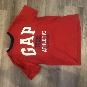 Gap T-shirt - Röd gap t-shirt med vita och mörkblå detaljer. Storlek XL kids men passar som en S-M dam.