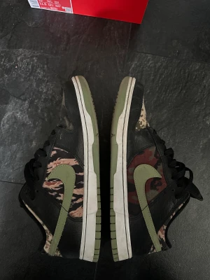 Nike Dunk camo  - Säljer nu mina Nike Dunk Camo då de ej passar mig. Köpta begagnade men är i väldigt gott skick,9/10! Kvitto samt låda finns!