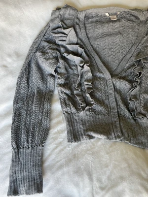 Kofta - Grå kofta supersöt från h&m. Med volanger & fint mönster. Använd men i fint skick. Stl 34. 🦋 Superfin till jeans eller en klänning. 