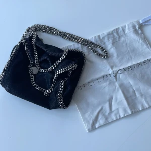 Stella McCartney tiny falabella väska  - Nästan helt oandvänd väska, köpt för 4500kr!  Väldigt bra skick, den är svart med lite skimmer och silverkedjor! Tygpåse kommer med💕
