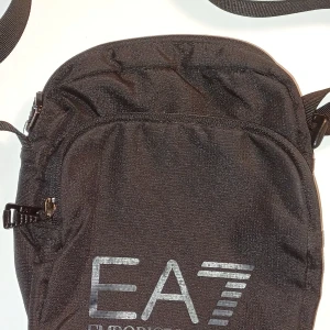 Emporio Armani väska - Helt svart bpde bak och fram. Knappast använd då jag inte haft användning av den. 