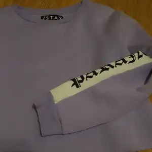 Lavendel färgad sweatshirt med text detaljer. Mjuk och fluffig på insidan. Endast använd ett fåtal gånger.
