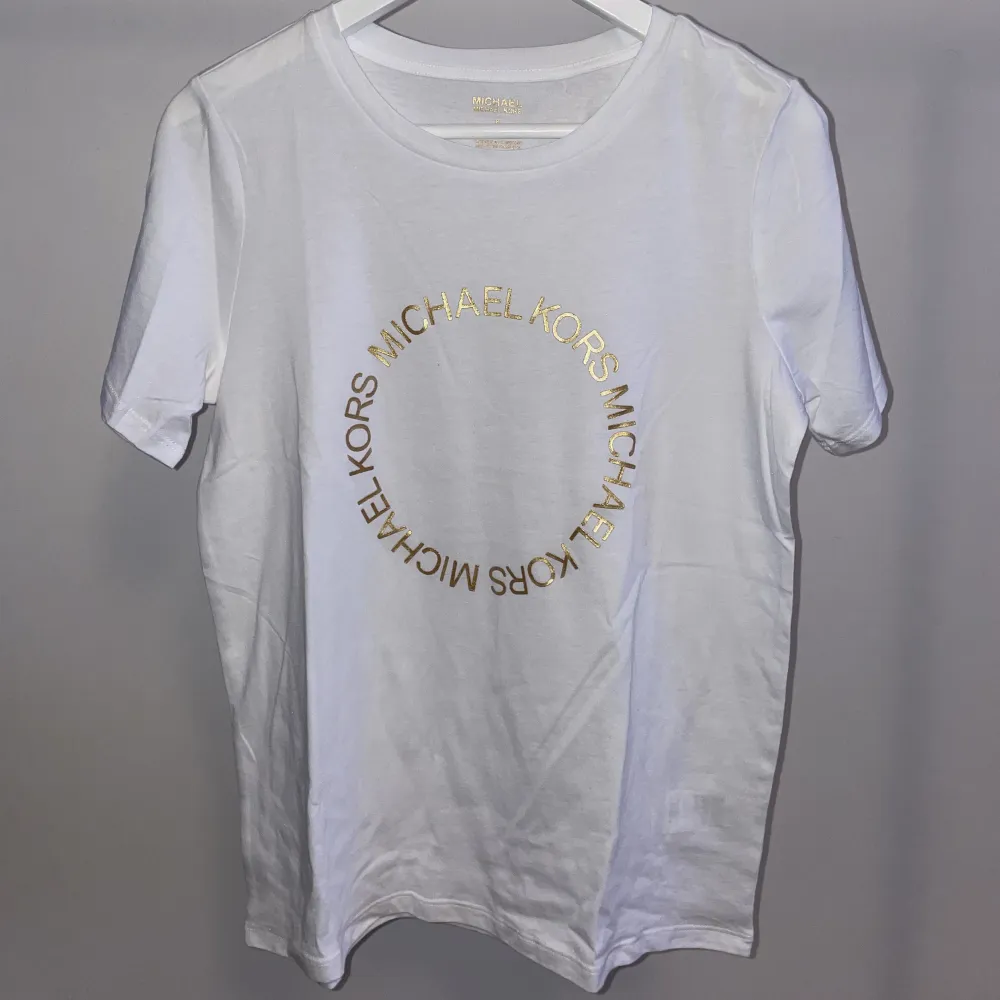 T-shirt med tryckt guldtext, från Michael Kors. Helt ny, aldrig använd. Funkar till uppklätt men också till vardags.  Nypris 1000kr.  Pris går att diskutera, ge förslag . T-shirts.