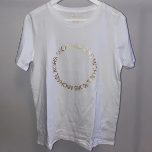 T-shirt med tryck, Michael kors  - T-shirt med tryckt guldtext, från Michael Kors. Helt ny, aldrig använd. Funkar till uppklätt men också till vardags.  Nypris 1000kr.  Pris går att diskutera, ge förslag 
