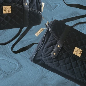DKNY väska - Nypris: 1699 kr. Mått: Ca 30 cm bred. DKNY väska med gulddetaljer, handtag och justerbar axelrem/crossbodyrem i läder. Dustbag medföljer. Rymmer mycket! Nåt pyttelitet märke på baksidan. Annars 100% nyskick, även DKNY-hänget.