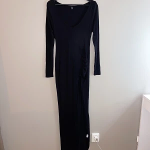 Svart långklänning - Svart långklänning i skönt tyg. Aldrig använd. Slits på benet. 