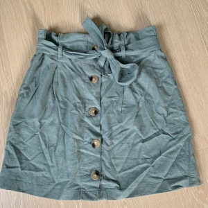 Grön linnekjol Gina Tricot - Grön linnekjol med knappar från Gina Tricot. Använd ett fåtal gånger 