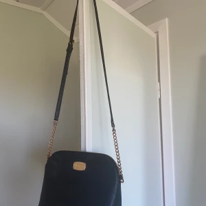 Mikeal Koers väska - Svart liten väska från MK, bra skick. Väskan är crossbody med ett smalt band. Perfekt för att få plats för kvällen ute eller en dag på stan. Mobil, plånbok, nycklar och solglasögon får plats på samma gång!