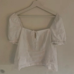 Blus - Superfin vit blus med liten detalj framtill. Köpt på H&M och aldrig använt. Storlek S-L beroende på hur tajt man vill ha plagget.