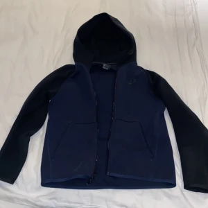 Nike Tech Svart/Navy (Gammal model) - Säljer också denna nike tech fleece hoodien med gamla modellen som är svår att få tag på! Inga hål eller fel på tröjan, lite tvättad dock så färgen är inte som en ny men fortfarande inte illa! Storlek S