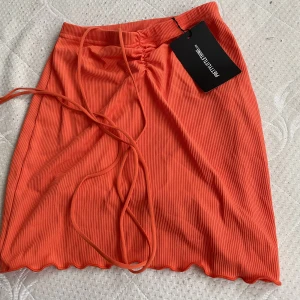 Orange kort kjol - En kort orange kjol från PLT. Strl S. Säljer pga för igen, skulle beställt M. Den är relativt kort och sitter tight. 