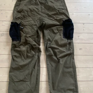 Green cargo parachute pants - Green cargo gorpcore parachute pants, använda, bra skick med några fläckar från målning.