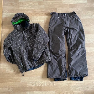 Skidjacka + byxor (brunt)  - Skidställ, jacka och byxor i brunt. Unisex.  Strl jacka: xs Strl byxor: s   Sitter mycket baggy på mig som är 160 cm lång. Generellt i fint skick men lite slitet vid byxslutet.   Många fickor och specifik ficka för liftkort på jackärmen. 