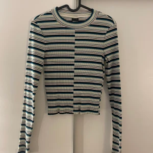 Randig Gina topp - En topp från Gina Tricot, använts en gång och är i bra skick. Den är grön, svart, blå, vit och brun randig.