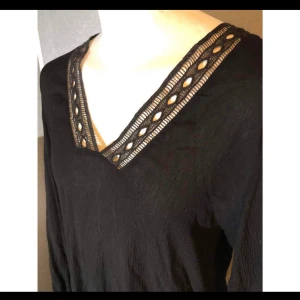 Svart blus med broderi - Svart lång blus med broderier och v ringning. Storlek 38.