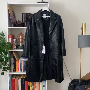 Svart läderkappa - En jättesnygg helt oanvänd kappa i fejkläder från Berskha, med lappen kvar. Köpt i Barcelona, strl s. Använd gärna köp nu-funktionen!💗