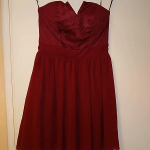Axelbandslös klänning 36 - Vinröd klänning med spets upptill. Axelbandslös.i mycket fint skick 