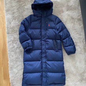 Ralph lauren dunjacka - Blå dunjacka från Ralph lauren. Storlek 150, passar mig som är 160 cm och har XS. Ett litet hål som inte syns på ärmen. Fler bilder skickas vid intresse. 