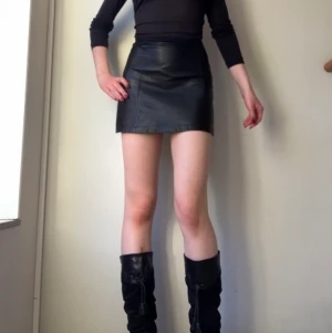 Läder kjol  - Kort läderkjol köpt på Beyond Retro. Bra kvalitet. Jättesnygg till boots.