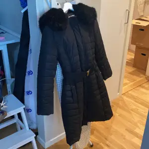 Long puffer coat from French Connection with faux fur hood and elasticated waist belt