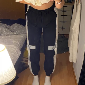 Svarta byxor med reflex - Sköna svarta byxor med en vit rand på sidan och en liten rektangel med reflex. Står att det är xl men de sitter som M