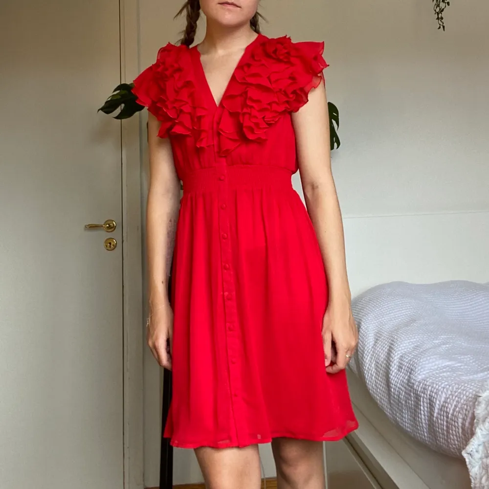 En röd klänning från H&M med knäppbara knappar och volang. 100% polyester. Tvättas i 40°C. ✨. Klänningar.