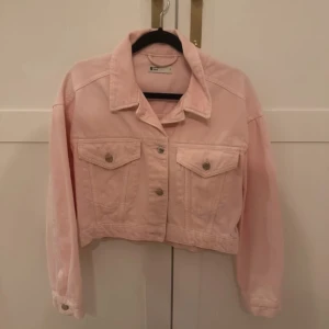 Rosa croppad jeansjacka - Säljer en snygg rosa croppad jeansjacka från Gina Tricot. Jackan har en klassisk krage och knappar framtill samt på ärmsluten. Perfekt för en cool och avslappnad stil.