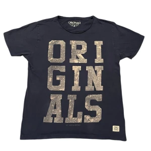 Svart t-shirt från Jack & Jones - Snygg svart t-shirt från Jack & Jones med stort 'ORIGINALS' tryck i grått på framsidan. Perfekt för en avslappnad stil. Tillverkad i mjukt material för extra komfort.