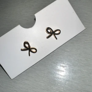 Guldörhängen med rosettform - Snygga små örhängen i guld med en stilren rosettform. Perfekta för att ge en elegant touch till din outfit. Lätta att bära och passar till många olika stilar.