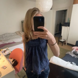 Mörkblå blus från Rut m.fl. - Säljer en söt mörkblå blus från Rut m.fl. med fina broderade detaljer runt halsringningen. Blusen är ärmlös och har en luftig passform, perfekt för varmare dagar. Passar bra till både jeans och kjol. 🌟