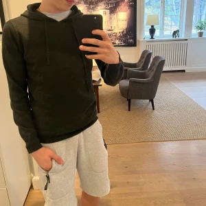 Merinoull hoodie - Säljer en stilren mörkgrön hoodie från Ahlquist Clothing i storlek S. Tröjan har en klassisk design med huva och snören. Go kvalitet och fungerar till det mesta! Nypris 1000kr ( MERINOULL) Han på bilden är 176 